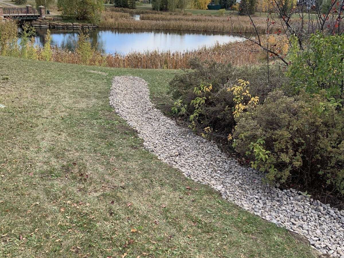 New overland spillway and rock-lined swale to a stormwater pond